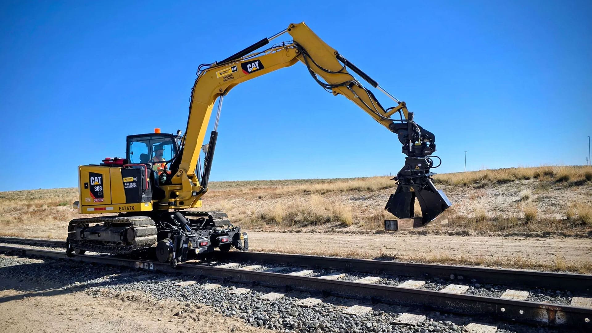 DymaxRail Hydraulic Clam Cribbing Bucket mounted on Cat 308 excavator with hi-rail gear, on-track maintenance operation
