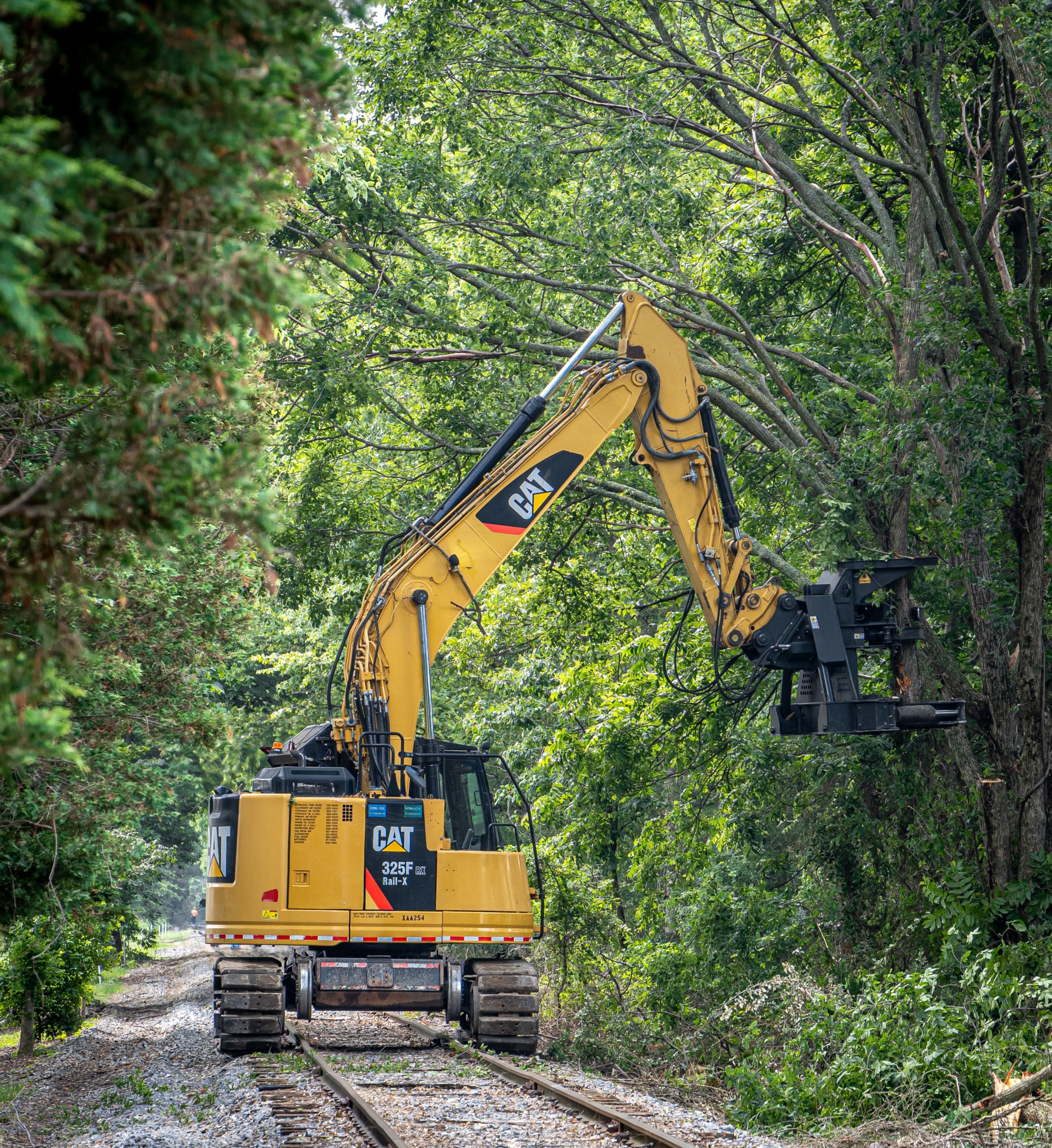 Cat excavator using Dymax 21" tree shear to trim branches overhanging railroad
