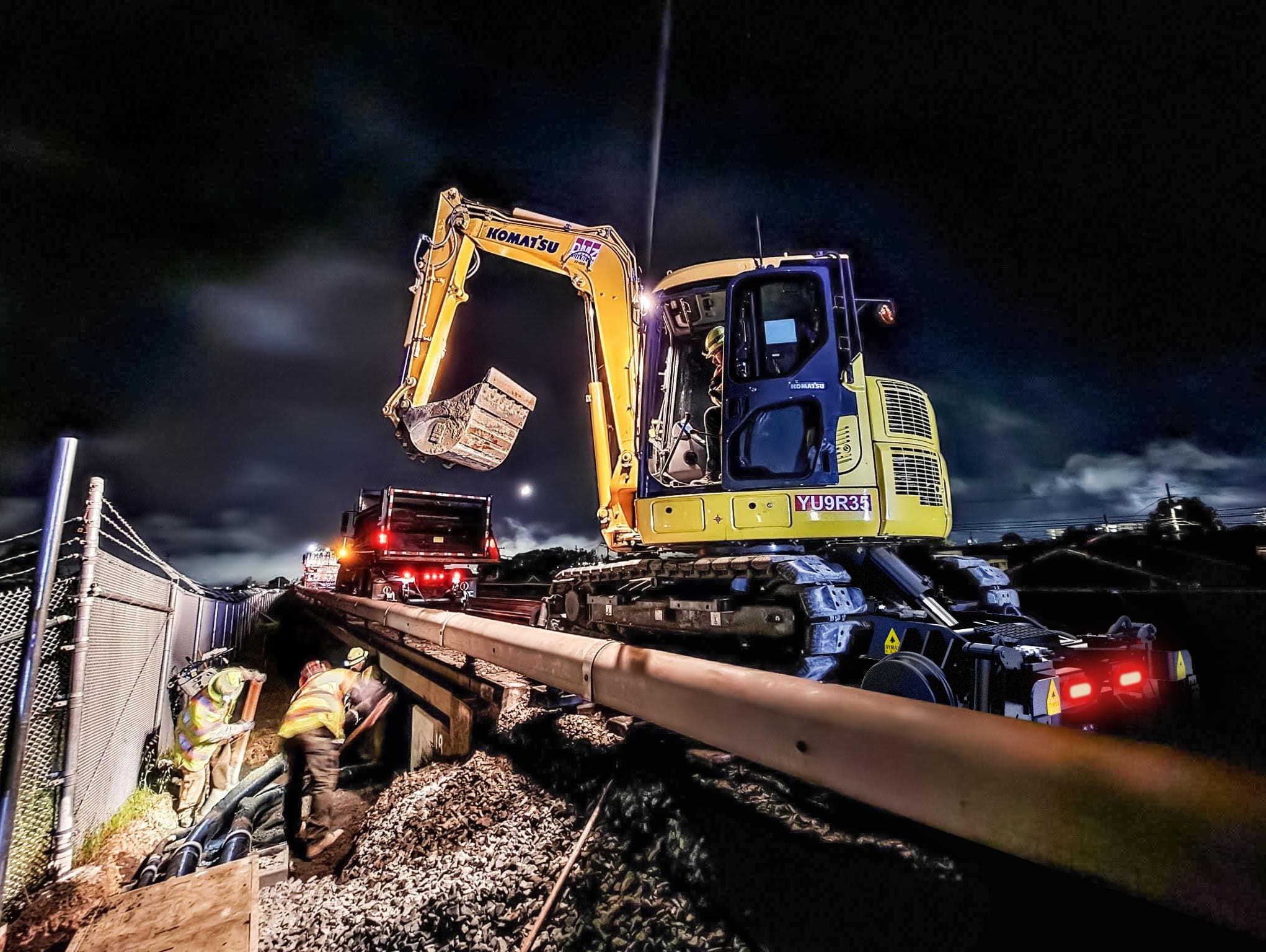 Hi rail excavator attachment working at night reparing bridge
