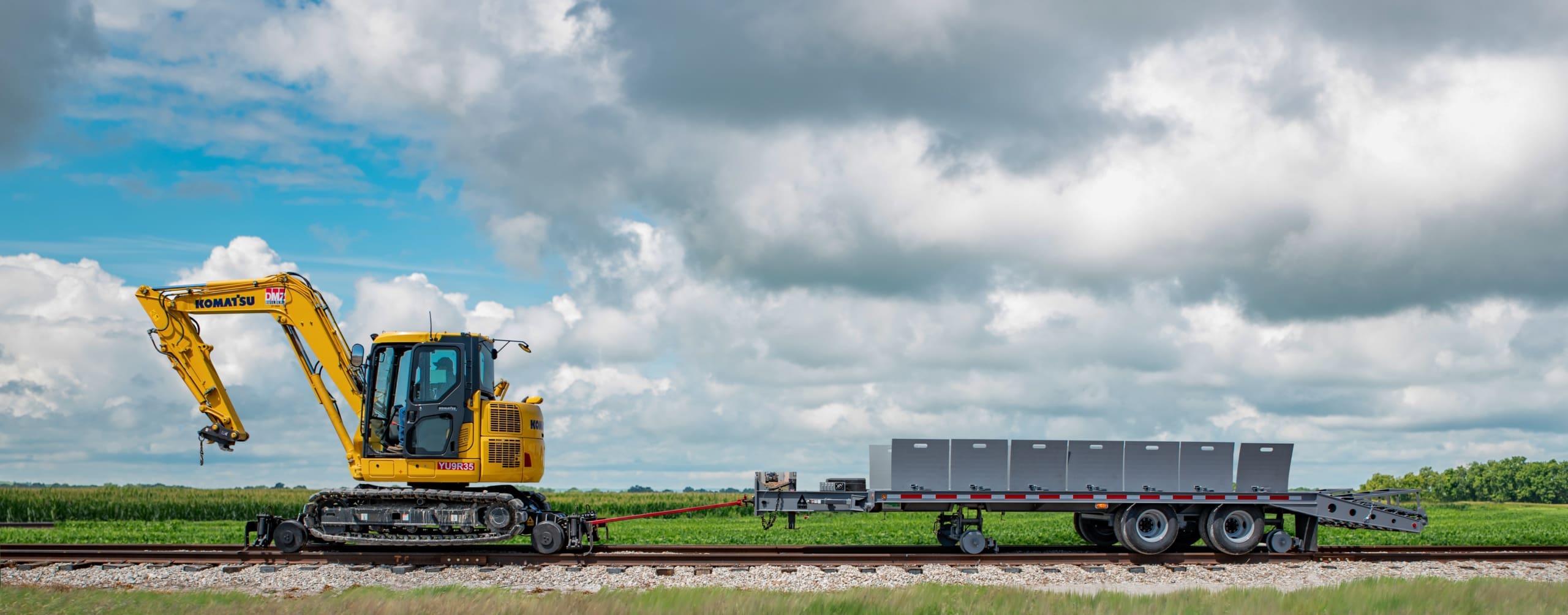 Komatsu excavator pulling a hi rail tailer with road and rail wheels