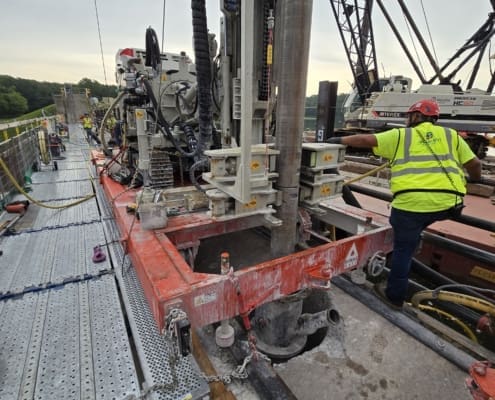 Close-up of DymaxRail cart with drilling equipment positioned directly over the dam deck during deep anchor shaft drilling.