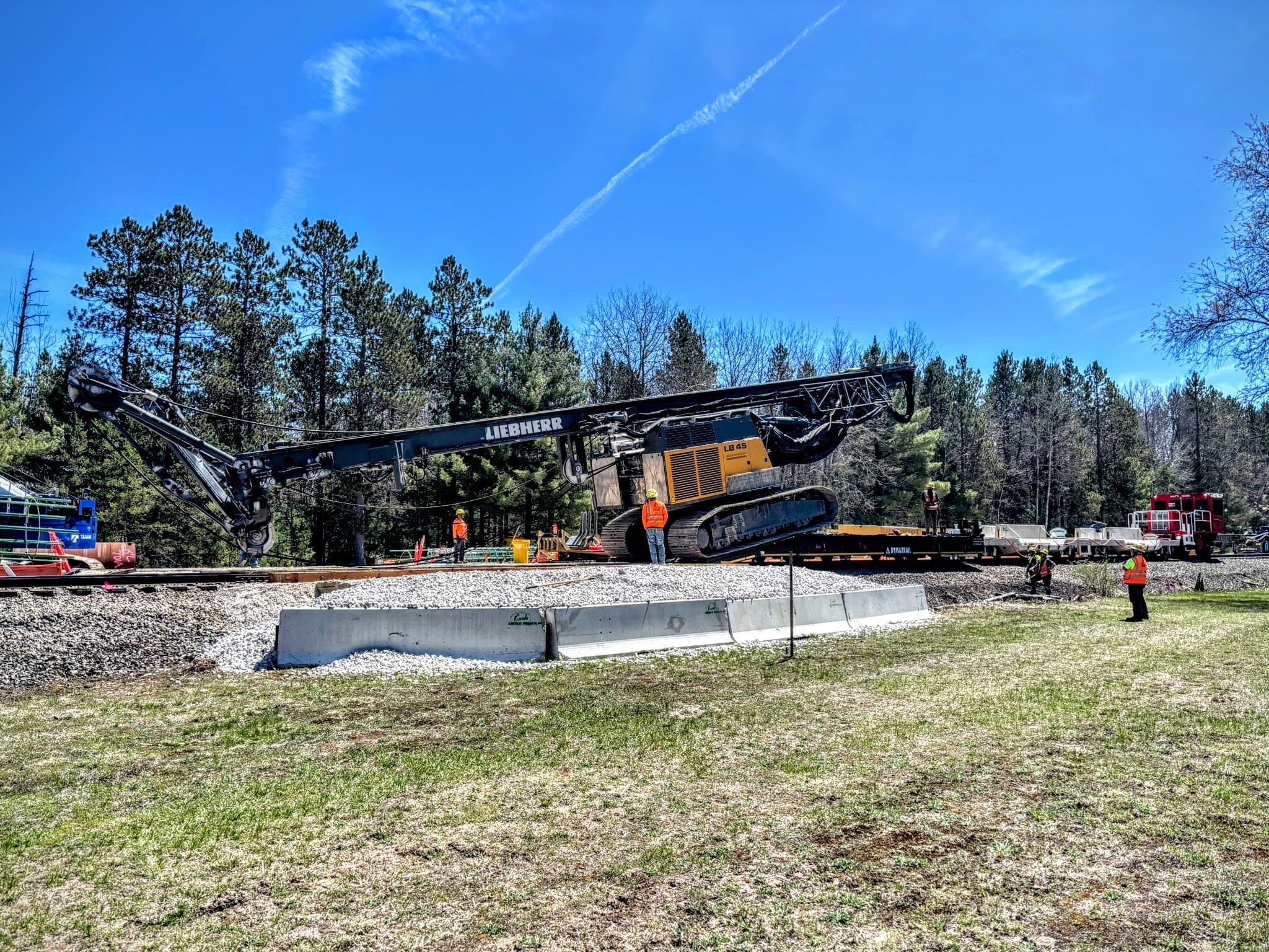 Drilling and foundation equipment delivered and staged on the track for bridge construction work.