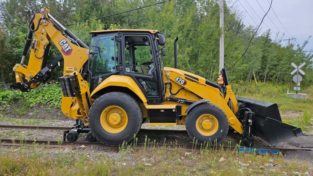 Caterpillar 420 backhoe equipped with the Dymax LoPro Rail Rider hi-rail system on railroad track