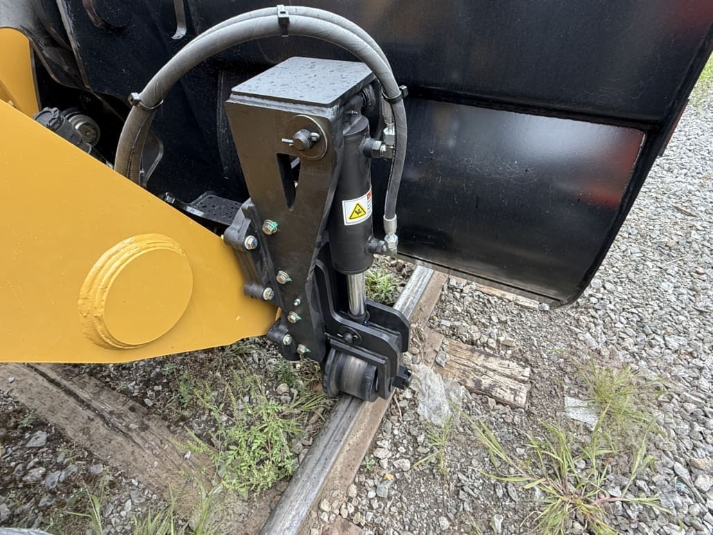 Close-up of Dymax LoPro Rail Rider front railgear mounted to a Caterpillar backhoe loader bucket