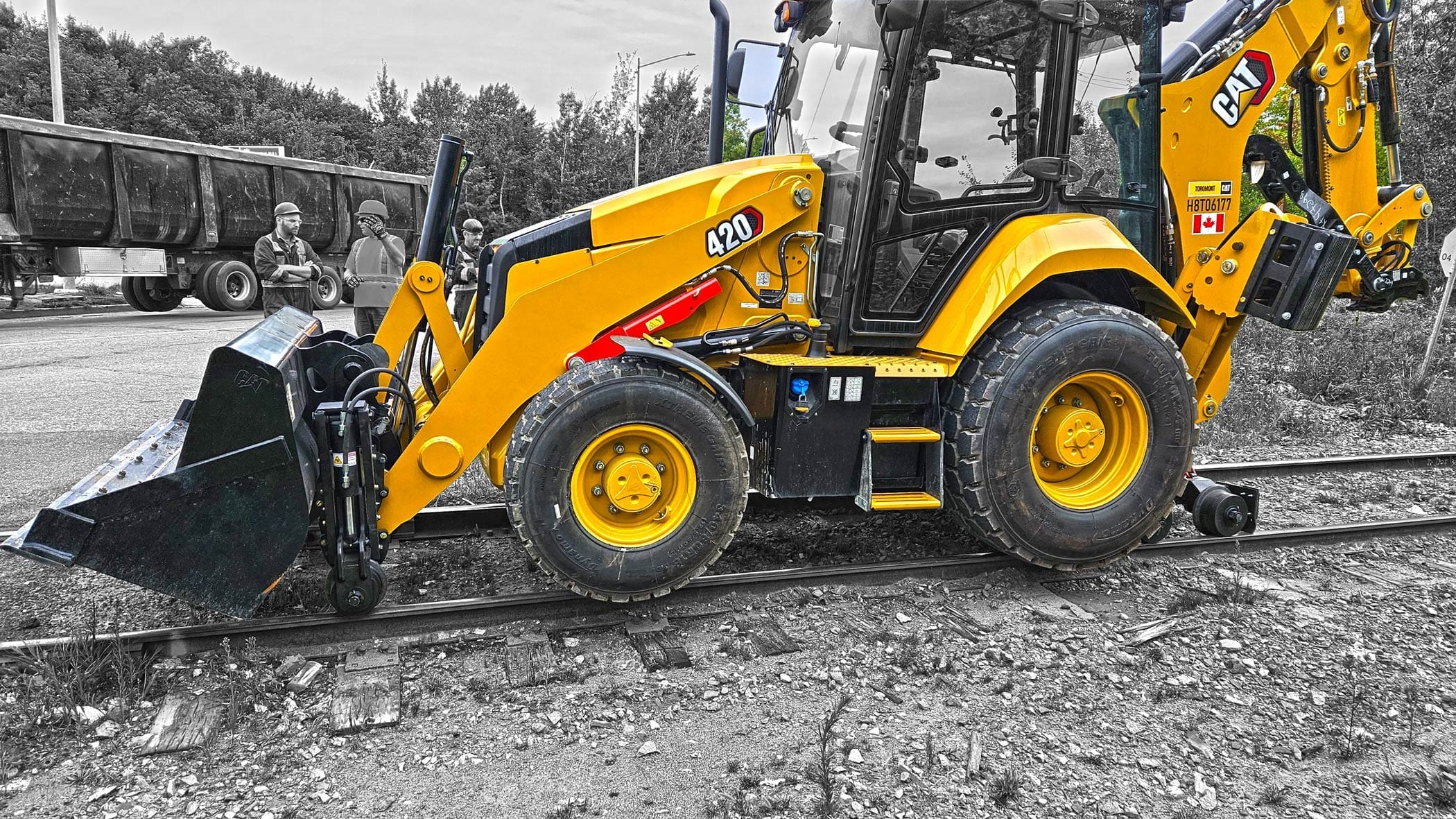 Caterpillar backhoe equipped with Dymax LoPro Rail Rider hi-rail system operating on CN railroad track