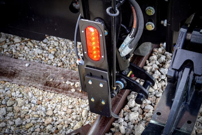 Close-up of the Dymax Rail Rider X2-15T solar-powered red and white directional LED lighting that illuminates track based on travel direction from a self-contained power source