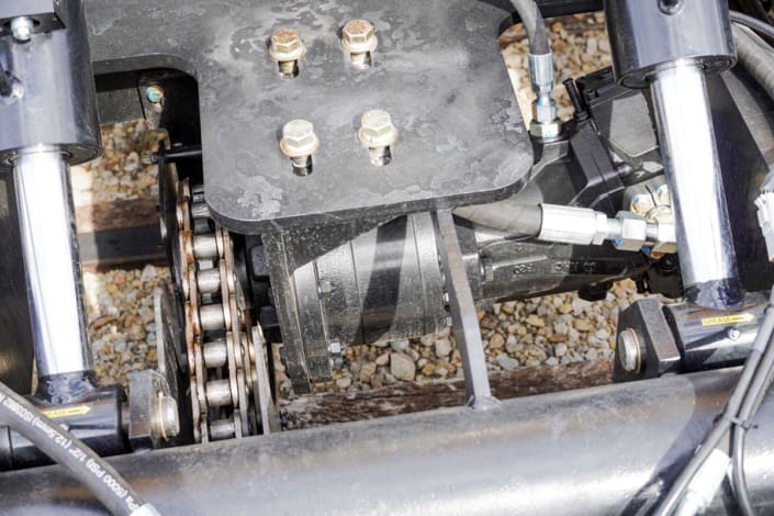 Close-up of the Dymax Rail Rider X2-15T 2-speed hydrostatic drive system delivering 18-20 mph travel with strong towing and grade-pulling power, operated through the standard excavator travel pedals