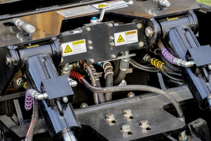 Close-up of the Dymax Rail Rider X2-15T pre-hosed hydraulic bulkhead connections with labeled hoses, integrated manifolds, and Magnum filtration for simplified dealer or in-shop installation