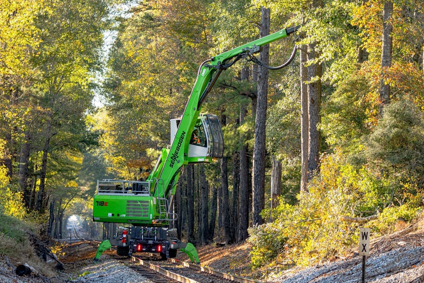 Sennebogen 718 heel excavator with Dymax Rail Rider WX4S hi-rail system performing vegetation management along rail right-of-way.