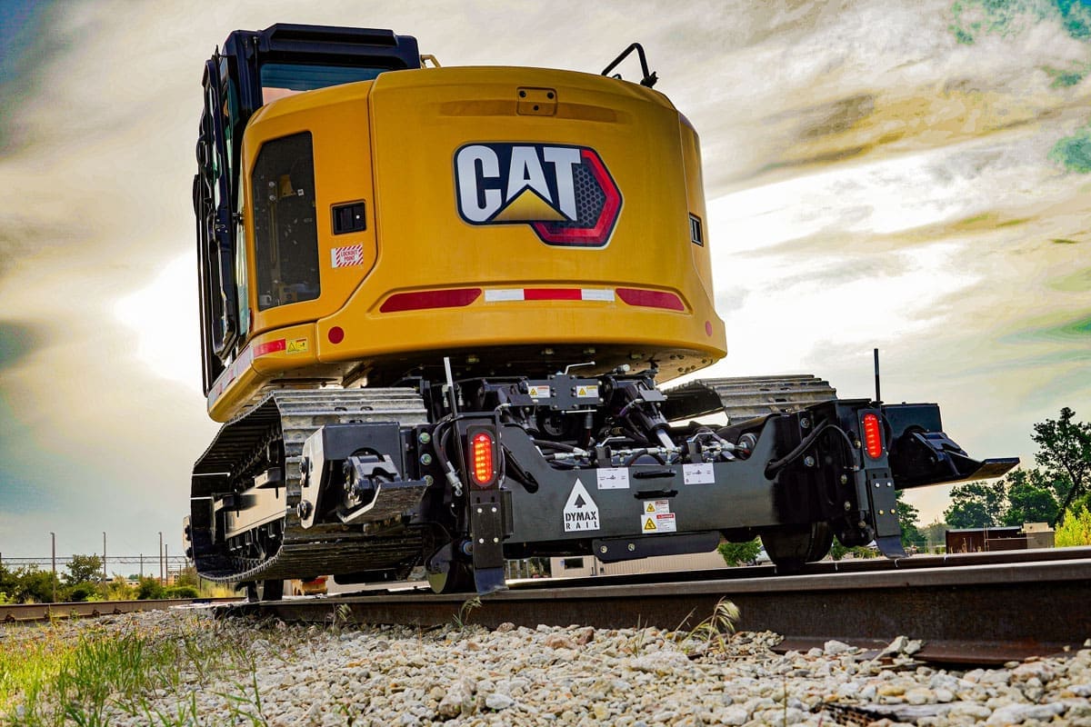 Rear view of a Cat track excavator equipped with the Dymax Rail Rider X2 detachable hi-rail system, illustrating how a non-modified excavator retains resale value at end of lifecycle