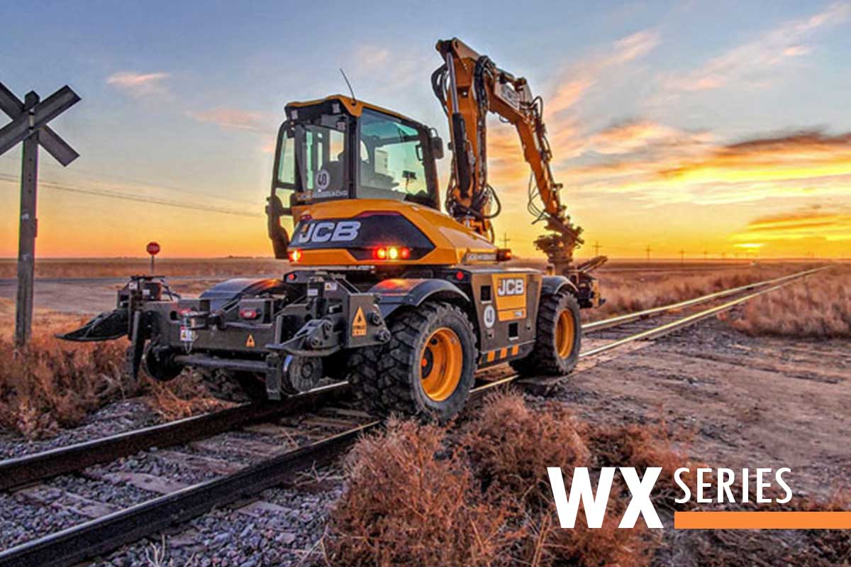 Hi-rail wheel excavator on rails at sunset Wheel excavator equipped with DymaxRail Rail Rider WX hi-rail guidance system operating on railroad track