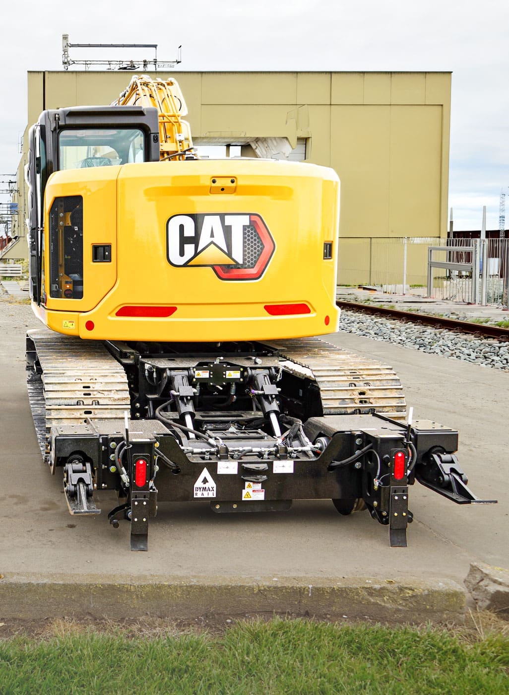 Dymax Rail Rider X2 hi-rail attachment installed on Cat track excavator Cat track excavator with the Dymax Rail Rider X2 detachable hi-rail attachment installed, showing the fully supported frame and modular front and rear hi-rail assemblies with no permanent machine modifications